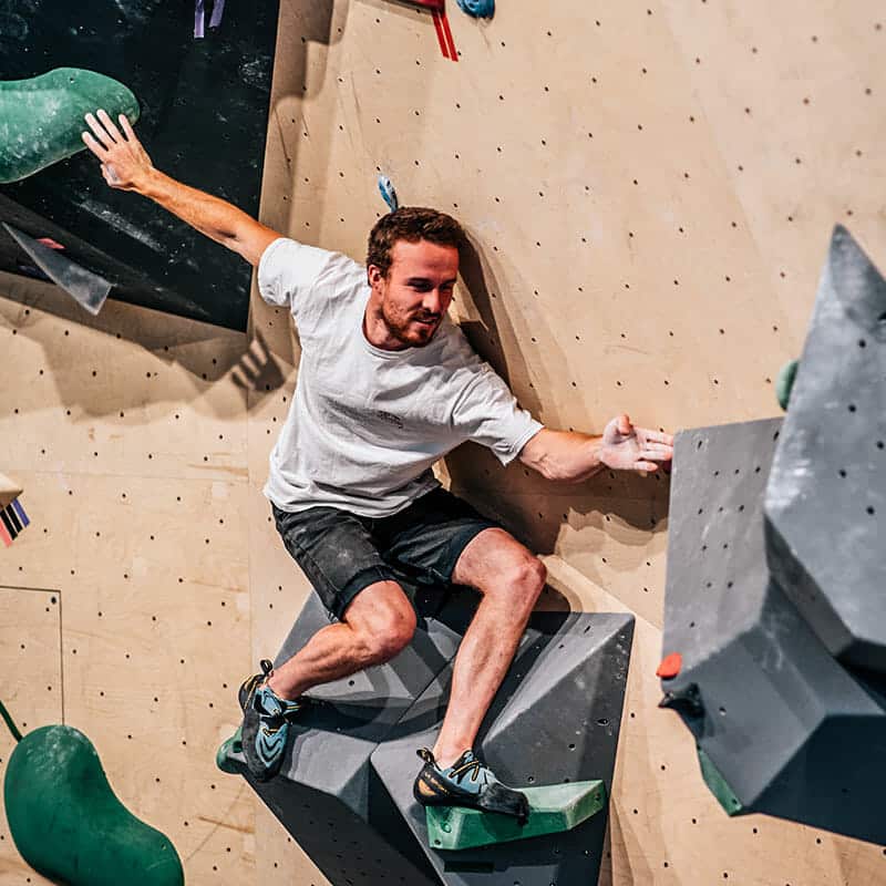 Comment débuter en escalade, grimpeur sur un des mur de Climbing District